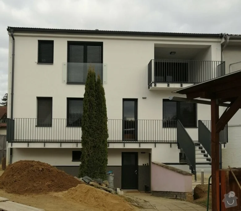 Moderní černá kovová zábradlí na balkóně a schodišti bílého domu.