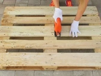 Ruce v bílých rukavicích řezají paletu na venkově.