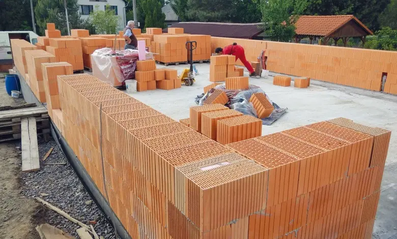 Stavba cihlové terasy u soukromého domu s dělníky.