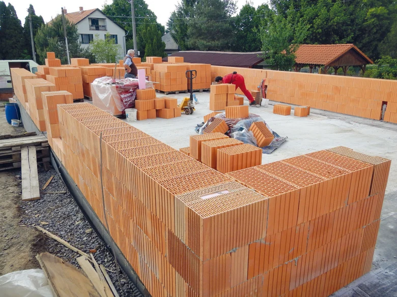 Stavba cihlové terasy u soukromého domu s dělníky.