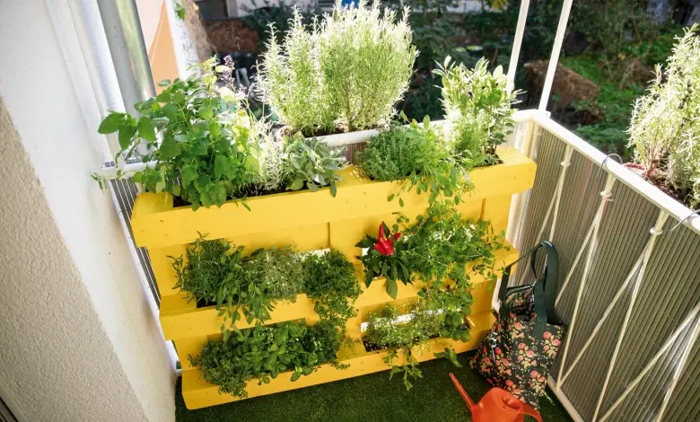 Žlutý paletový květináč s bylinkami na balkóně ukazuje rozložení váhy.