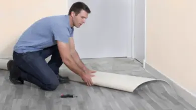 Muž instaluje podlahovou krytinu před dveřmi s mezerou.