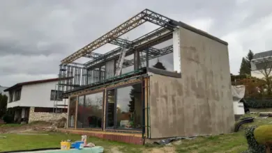 Stavba domu z kontejnerů s viditelným ocelovým rámem a skleněnými panely.