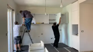 Muži sestavují bílé kuchyňské skříně v bytě.