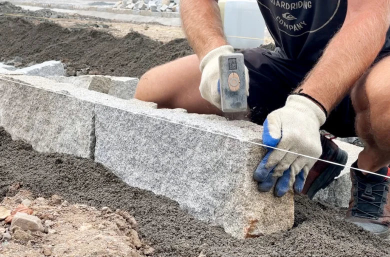 Montáž žulových dlažebních kostek s použitím laserové hladiny.