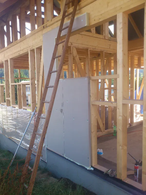 Stodola v dřevěném rámu s instalací izolace na stavbě.