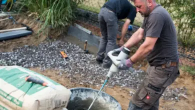 Muži míchají beton na stavbě s pytli cementu.
