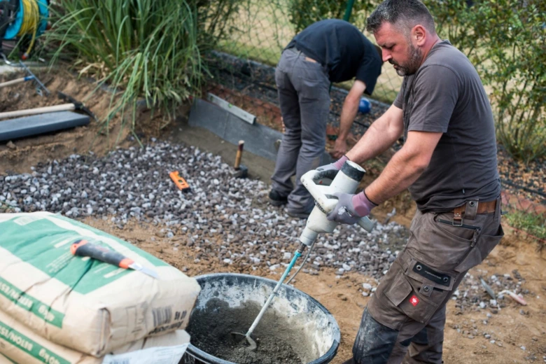 Muži míchají beton pro základ na stavbě s štěrkem.