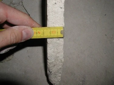 Měření šířky betonové mazaniny páskou pro kontrolu správného provedení.
