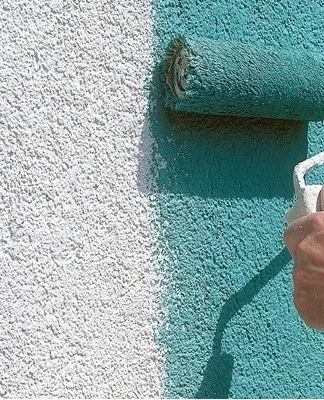 Ruční natírání polystyrenu válcem tyrkysovou barvou.