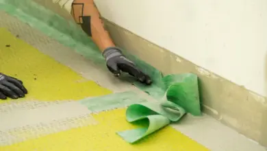 Montáž dlaždic na podlahu s aplikací zelené lepidlo u zdi.