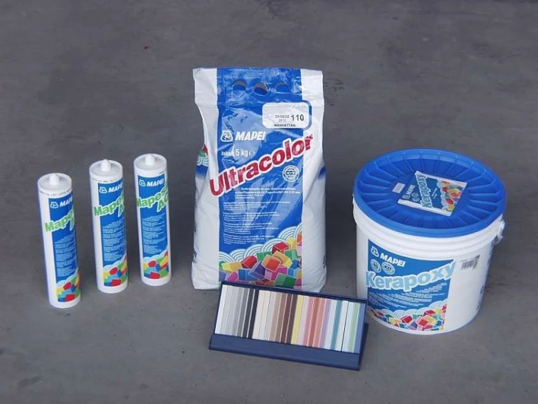 Materiály pro vyplnění spár dlažby včetně lepidla a těsnicí hmoty značky Mapei.