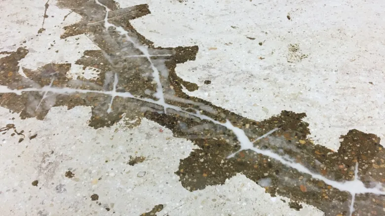 Nerovná betonová podlaha s prasklinami a skvrnami před vyrovnáním.