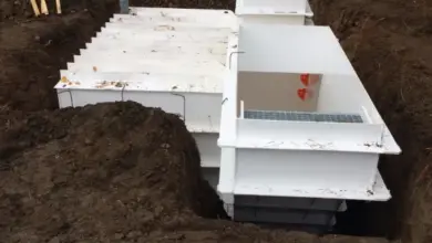 Bílý plastový sklep se instaluje do zemině na staveništi.