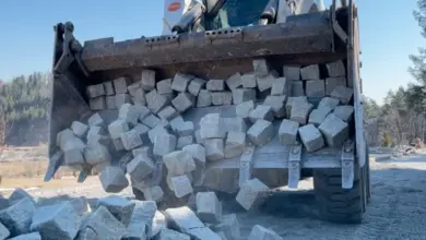 Nabíječka vykládá žulové dlažební kostky na zem.