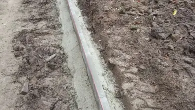 Instalace obrubníku do výkopu s viditelným betónem.