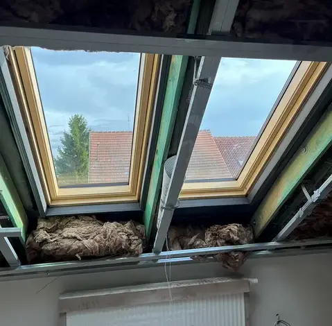 Krovové trámy s izolací mezi nimi v interiéru.