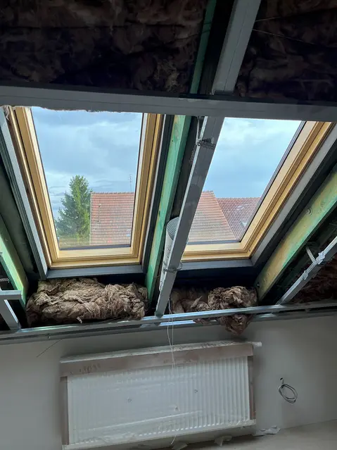 Krovové trámy s izolací mezi nimi v interiéru.