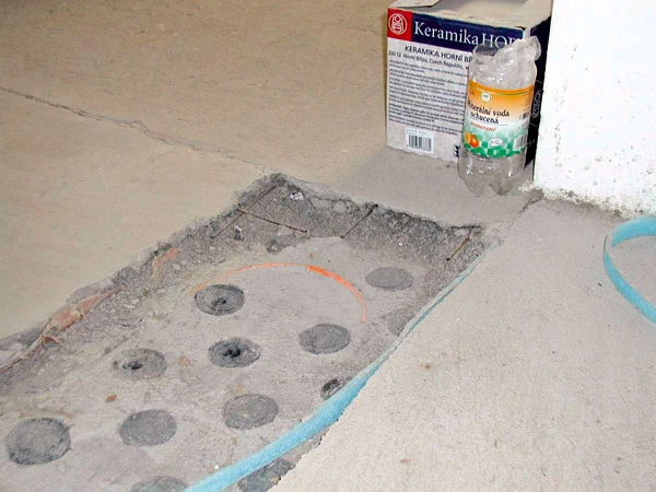 Betonová podlahová mazanina s otvory pro instalaci před dokončením.