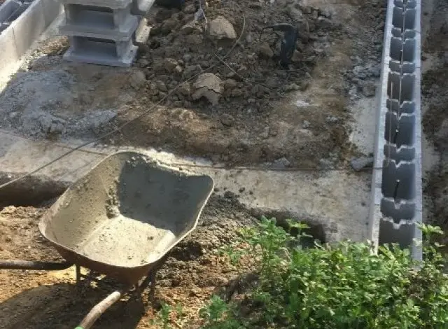 Stavba betonového základu z bloků v jámě s nářadím.