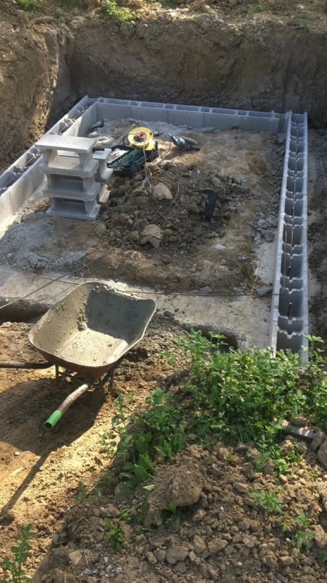 Stavba betonového základu z bloků v jámě s nářadím.