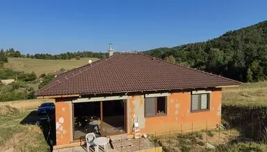 Dům s novou střechou v přírodě jako ukázka stavby.