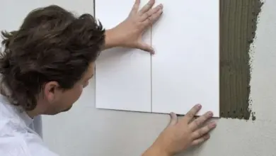 Muž leští bílé dlaždice na omítnutý štít krok za krokem.