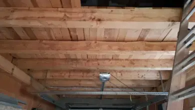 Neukončený garážový strop s dřevěnými trámy pro zakrytí.