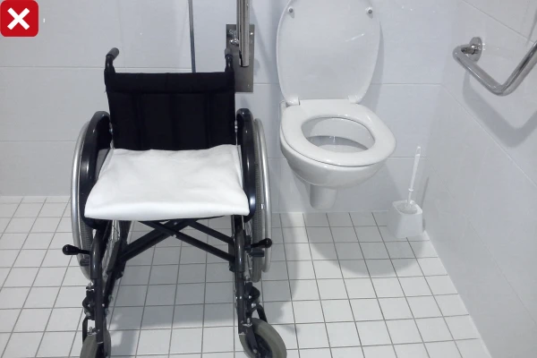 Křeslo pro invalidy vedle přístupného záchodu v koupelně