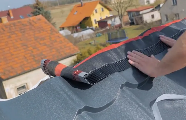 Ruční pokládka černého asfaltového krycího materiálu na střechu.