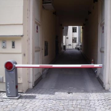 Sekční brána s červenobílou pákou na ulici.