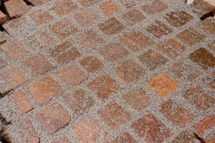 Pohled na dlažbu s vyplněnými spárami mezi kostkami.