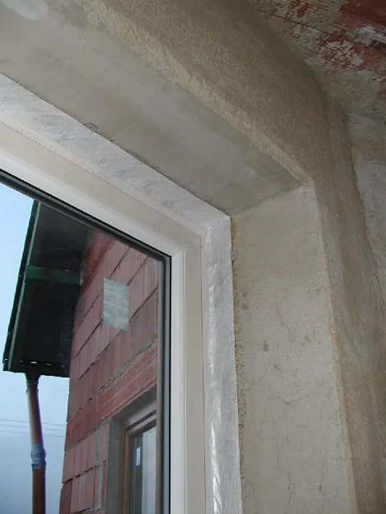 Detailní pohled na instalaci okna do podkroví s nedokončenými zdi.