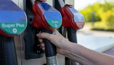 Ruka drží čerpadlo benzínu na benzinové stanici.