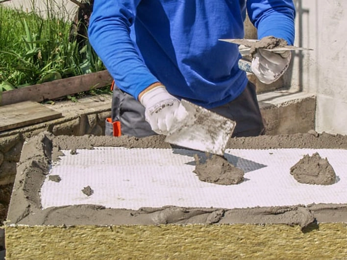 Montáž minerální vaty s omítkou pomocí špachtle na fasádu.