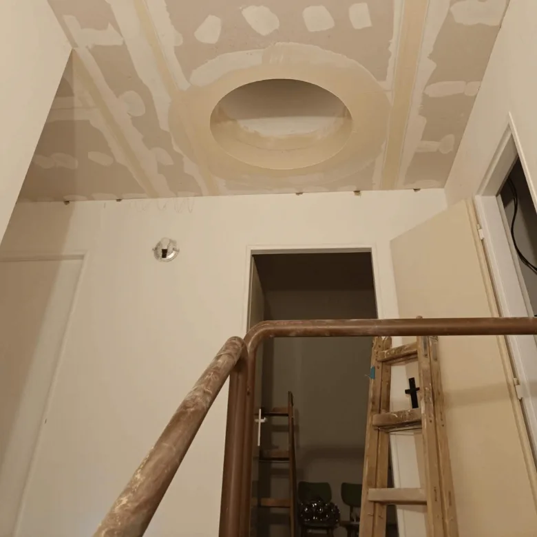 Instalace sádrokartonu v interiéru - viditelné spoje a kruhový otvor na stropě.
