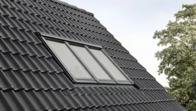 Moderní střešní okno v tmavých taškách na šedém střechu.