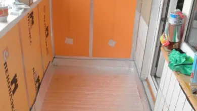 Balkon s oranžovou izolační fólií a odrazivou podlahou během stavby.