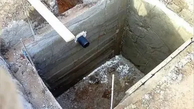 Zemní toaleta s betonovými panely a výpustním potrubím.