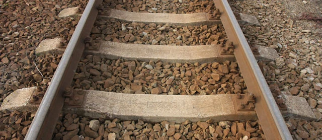 Betonový pražec mezi kolejnicemi na štěrku.