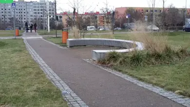 Asfaltový chodník v městském parku s trávníkem.