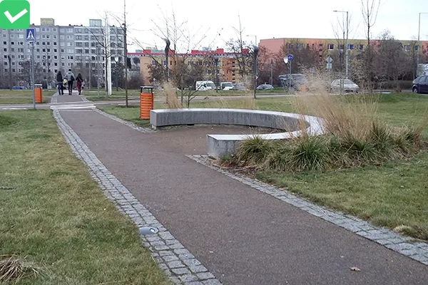 Asfaltový chodník v městském parku s trávníkem.