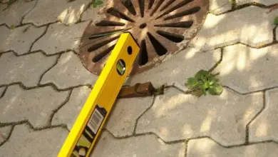 Žlutá úrovněř na kanalizační mřížce pro správný sklon vjezdu.