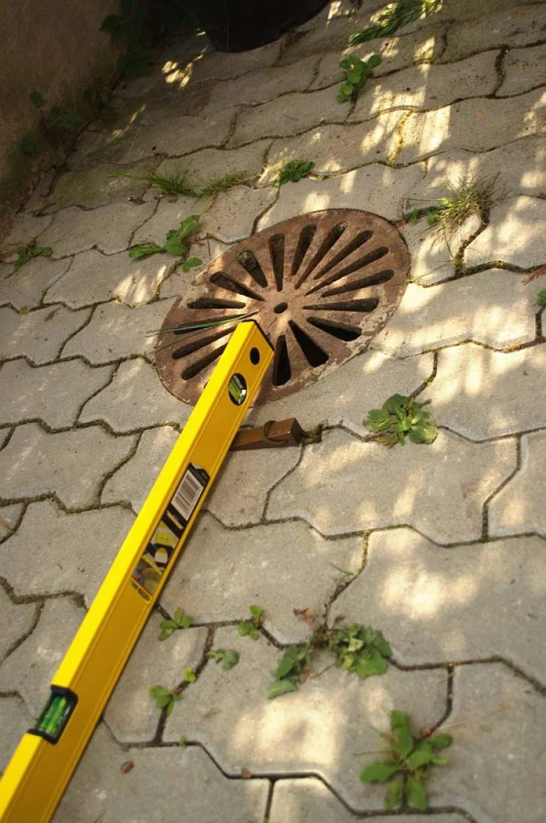 Žlutá úrovněř na kanalizační mřížce pro správný sklon vjezdu.