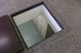 Otevřený poklop do suterénu ukazuje schodiště vedoucí dolů.