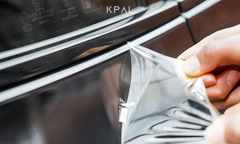 Ruka odstraňuje ochrannou fólii z povrchu sendvičového panelu.