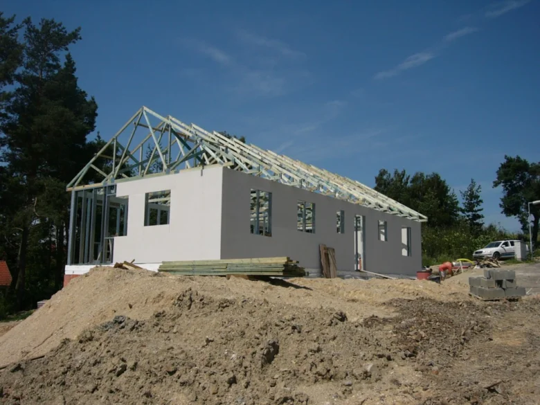 Stavba domu s odkrytou střechou na pozemku.
