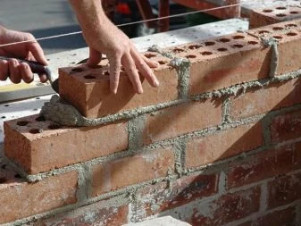 Ruční kladení cihel s maltou při stavbě zdi.