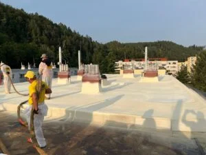 Pracovníci nanášejí izolační pěnu na střechu.