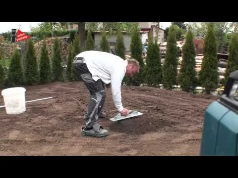 Muž vyrovnává zeminu před pokládkou asfaltového povrchu.